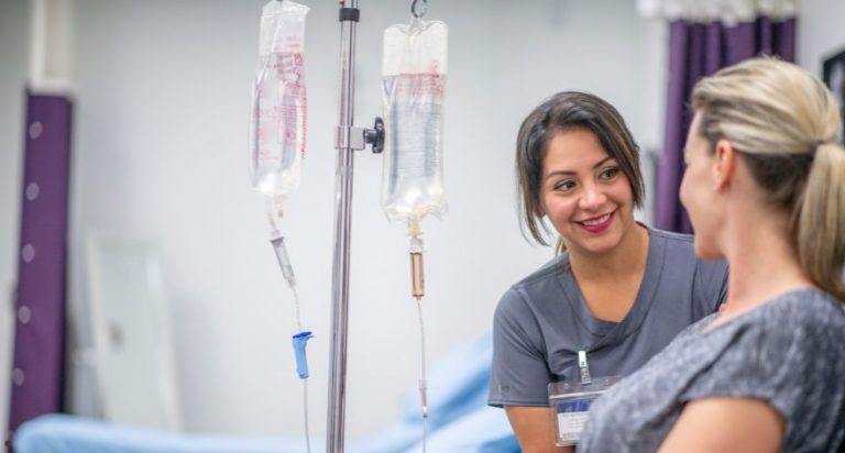 A patient sitting with a doctor, receiving IV treatment for aTTP.